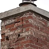 Weathered concrete crown and cap on top of a brick chimney