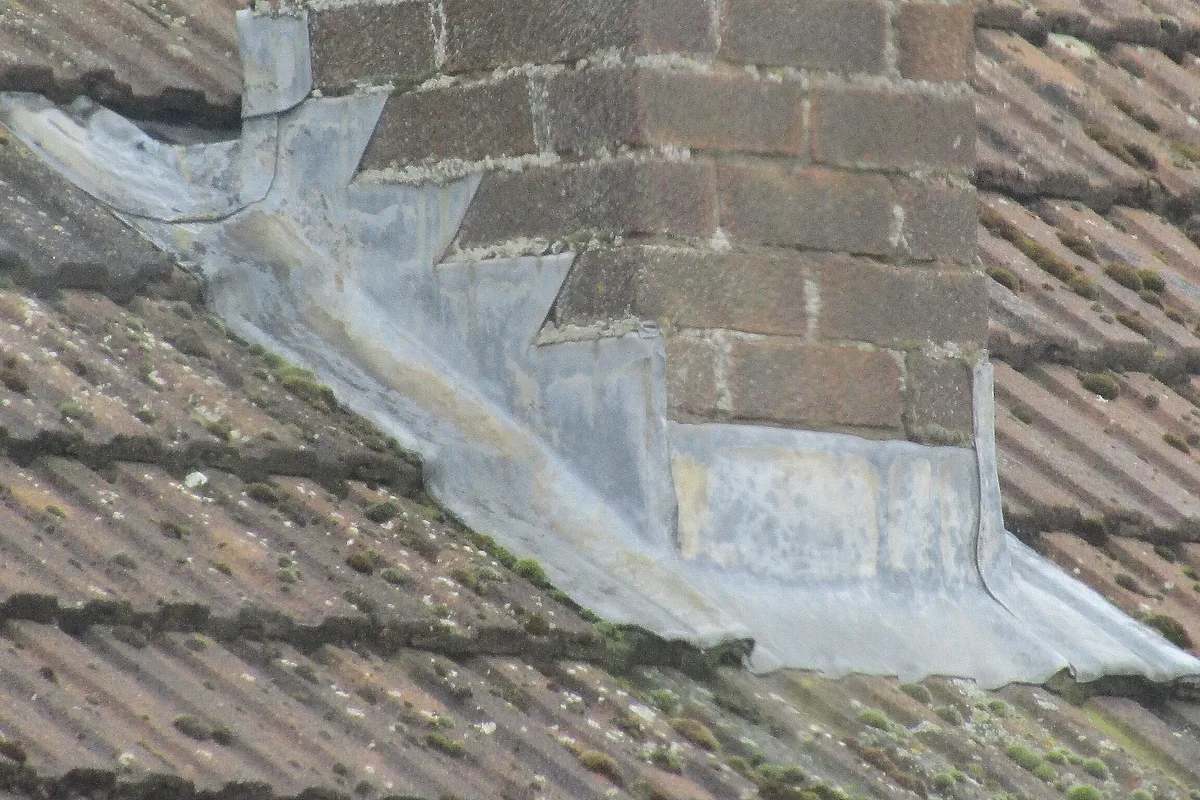 Stepped lead flashing sealing the joint between a brick chimney and a tiled roof