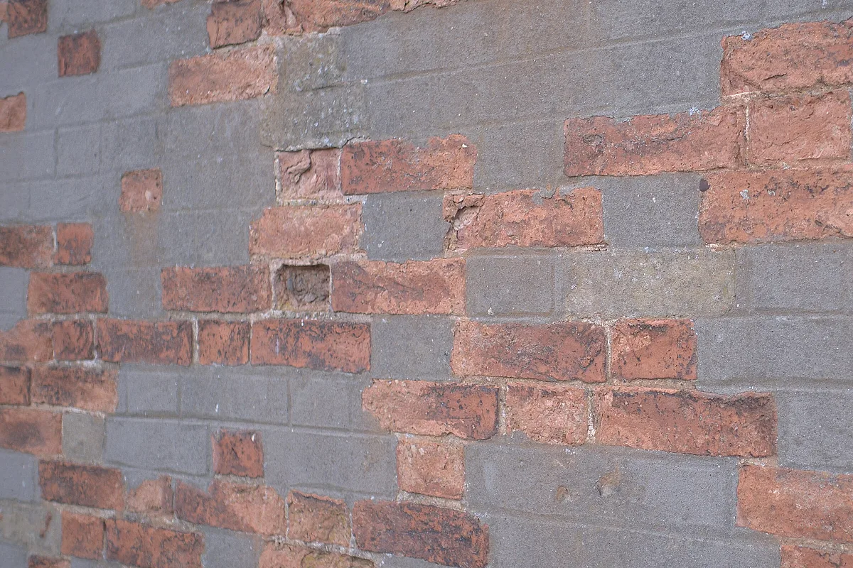 Brick wall with a patch of replacement bricks set in fresh mortar